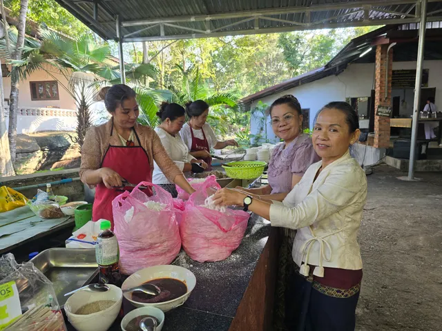 ແມ່ຄົວຊ່ວຍກັນຫໍ່ເຂົ້າ ແລະ ຈັດກຽມອາຫານດ້ວຍຮອຍຍິ້ມ.