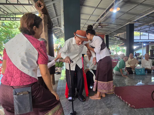 ລູກຫຼານຊ່ວຍປະຄອງຜູ້ເຖົ້າມາຮ່ວມສ້າງບຸນ.