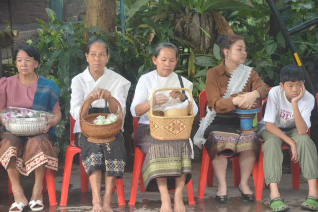 ຍາດໂຍມຖືກະຕິບເຂົ້າ ແລະ ຂັນເງິນ ນັ່ງລໍຖ້າຕັກບາດ.