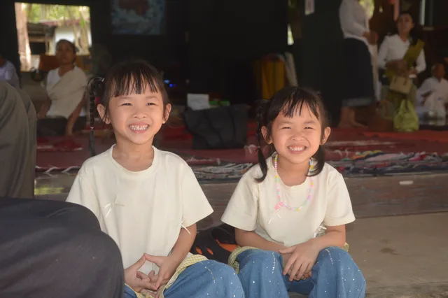 ເດັກນ້ອຍຍິ້ມແຍ້ມມາຮ່ວມບຸນເຂົ້າສະຫຼາກກັບຄອບຄົວ.