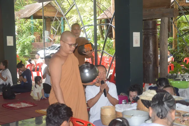 ພຣະສົງຖືສະຫຼາກສອງໃບ ຂະນະຜູ້ນຳບຸນປະກາດຊື່ຍາດໂຍມ.