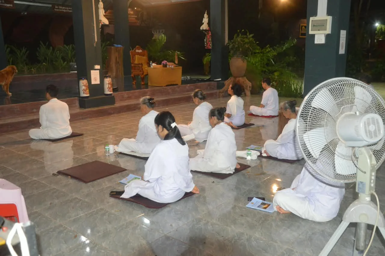 ບັນຍາກາດຍາມແລງ ຍາດໂຍມນຸ່ງຂາວນັ່ງພ້ອມກັນພາຍໃນສາລາ.